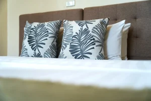Comfortable hotel bed with soft linens and tropical-pattern pillows at MySpace Hotel
