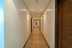 Hotel Comembo Brightly lit hotel hallway with wooden flooring and cream-colored walls.