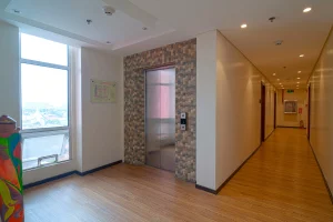 Hotel hallway with wood flooring, elevator, and a large window providing natural light.