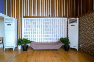 Modern hotel lounge area with a cushioned brown bench, indoor plants, and wooden wall accents.