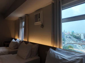 Twin beds by the window with a city view at MySpace Hotel.