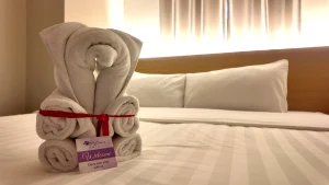 Towel art with welcome tag placed on a neatly made bed at MySpace Hotel.