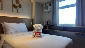 MySpace Hotel modern room in BGC with clean white bedding, towel art, and window view.