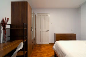 Bedroom interior featuring a study desk, wardrobe, and dresser with wooden finishes and clean minimalist design.