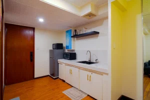 A compact kitchenette with a refrigerator, microwave, sink, and storage cabinets in a hotel suite in MySpace Windsor